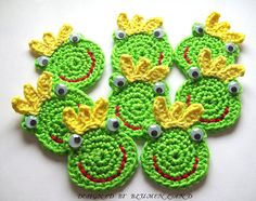 green crocheted frog appliques with yellow and red trimmings on white surface