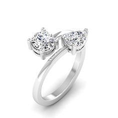 This exquisite two stone diamond ring features two pear and round shaped diamonds, creating a stunning and unique design that is sure to catch the eye. The diamonds are elegantly set in a high-quality metal band, making it a perfect choice for a special occasion or as a beautiful gift for a loved one. Metal: 14K Gold Setting Type: Prong Rhodium Finish: Yes, on White Gold Lab Diamond Details: Weight: 1.50 Shape: Round and Pear Number: 2 Average Cut: Very Good Average Color: F-G Average Clarity: V Pear-shaped Diamond Ring With Tension Setting, Elegant Teardrop Diamond Promise Ring, Modern Teardrop Diamond Ring For Anniversary, Pear-shaped Rings With Tension Setting For Anniversary, Timeless Pear-shaped Diamond Anniversary Ring, Pear-shaped Diamond White Ring For Anniversary, Pear-shaped Brilliant Cut Cubic Zirconia Diamond Ring, Pear-shaped Cubic Zirconia Diamond Ring With Brilliant Cut, Pear-shaped Diamond Ring In White Gold