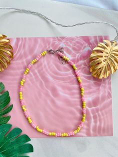 This necklace is waterproof so it's perfect for summer! It is 14 inches long and has a 2-inch extender chain so it can be adjusted to be 14-16 inches long! Handmade Pink Necklaces For The Beach, Pink Heishi Beads Necklace With Tiny Beads, Pink Heishi Beads Necklace, Trendy Yellow Necklace With Tiny Beads, Pink Necklace For Summer Festivals, Casual Pink Beaded Chain Bracelets, Casual Pink Beads For Festivals, Summer Beaded Necklaces With Round Beads, Summer Beaded Necklaces With Round Letter Beads