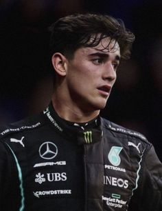 a close up of a person wearing a racing suit and looking off to the side