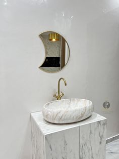 a bathroom with marble counter top and gold faucet on the wall, along with a round sink