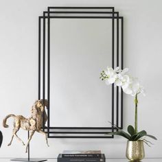 a mirror sitting on top of a table next to a vase with flowers