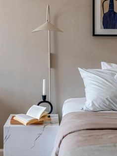 a bed room with a neatly made bed and a book on top of the nightstand