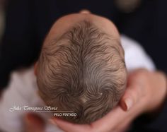 a person holding a baby in their hands with the hair on it's head