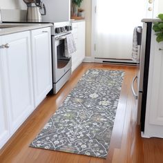 a kitchen with wooden floors and white cabinets, an oven, dishwasher and microwave