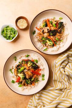 two white plates topped with rice and veggies