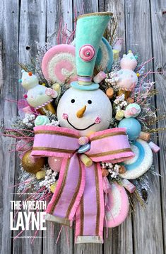 a snowman wreath on top of a wooden fence