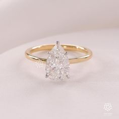 a yellow gold ring with a pear shaped diamond