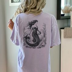 "Get ready to show your style with our back printed Vintage Mermaid T-Shirt! Perfect for a beach party, concert or or just a casual day out, this graphic tee is a must-have.  Proudly Printed on Comfort Colors® tees, for that insanely soft, vintage look and feel.  Without doubt, this will be your favorite shirt. With its vintage-inspired design, this shirt is perfect for those who love a boho, western, or retro look. The oversized fit and soft, comfortable fabric make it the perfect choice for a day on the ranch or a night out on the town. Made from garment-dyed fabric, this shirt has a unique, weathered look that will only get better with time. This cute shirt is perfect for any occasion. ⇒ PRODUCT DETAILS 100% ring-spun cotton 7/8\" double-needle topstitched collar Double-needle armhole, Cotton Mermaid Top For Summer, Mermaid Shirts, Mermaid Tshirt, Mermaid Top, Mermaid Shirt, Vintage Mermaid, Comfort Colors Tee, Mermaid Birthday, Vintage Inspired Design