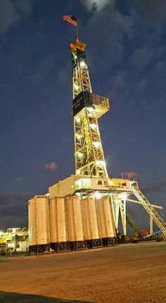 an oil rig lit up at night with the moon in the sky above it and clouds overhead