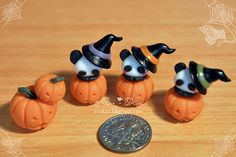 four small plastic pumpkins with witches hats on them and a penny sitting next to it