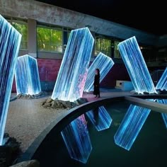 a woman standing in front of a pool with blue lights projected on it's sides