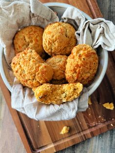 a bowl filled with muffins on top of a wooden cutting board next to a napkin