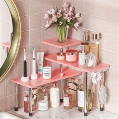 a bathroom with pink shelving and flowers on the shelf next to the mirror in front of it