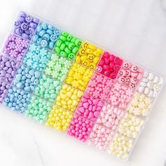 there are many different colors of beads in the box on the table, including one with smiley faces