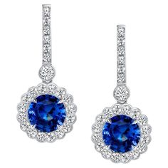 A classic pair of ”Princess Diana style” earrings, featuring 6.37 carats of Ceylon blue sapphires dazzle in divine platinum. The gorgeous sapphires are floating inside sparkling white halos of high-quality, scallop-set, round brilliant cut diamonds weighing 1.81 carats. Earrings are certified by the Gemological Institute of America.