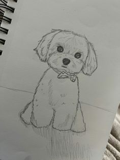 a drawing of a dog with a bow tie on it's collar sitting next to a notebook