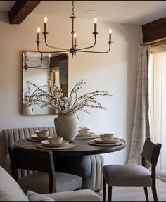 a dining room table with chairs and a vase filled with flowers on top of it