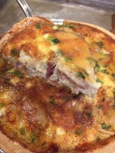 a close up of a pizza on a pan with a fork stuck in the crust