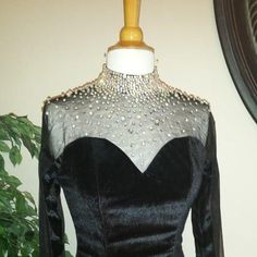 a black dress with silver sequins on the neckline and back, sitting on a mannequin