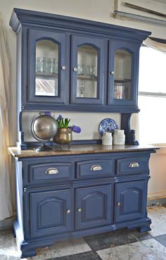 a blue china cabinet with glass doors and drawers