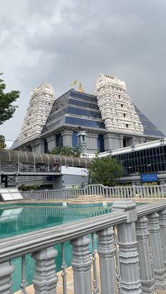 a large building that is next to a pool in the middle of a sidewalk area