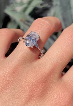 a woman's hand with a ring on it and an oval blue diamond in the middle