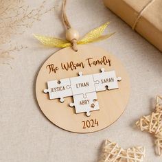 a personalized wooden ornament with puzzle pieces on it, next to a present box