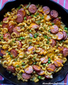 a skillet filled with macaroni and cheese, sausages and green peas