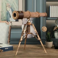 an antique telescope on a tripod in front of a bookshelf and potted plant