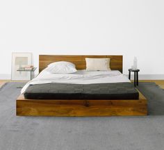 a bed sitting on top of a wooden platform next to a night stand and side table