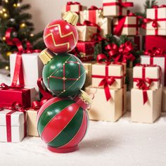 three christmas balls stacked on top of each other in front of presents and a christmas tree