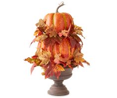 an arrangement of autumn leaves and pumpkins in a urn on a white background