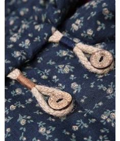 two buttons are attached to the back of a blue floral print shirt with white flowers on it