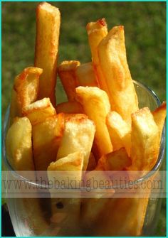 a glass bowl filled with french fries sitting on top of a green lawn covered in grass