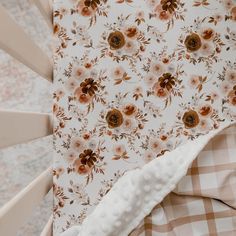 a baby crib with a flowered blanket on it's side and an umbrella in the background