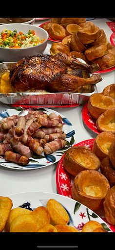 a table topped with plates and bowls filled with food next to baked goods on top of it