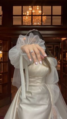 a woman in a white wedding dress with her hand on the back of her head