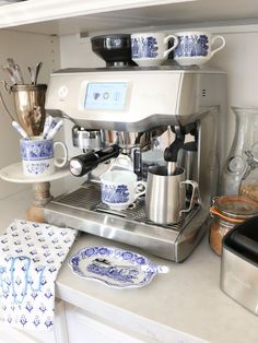 an espresso machine sitting on top of a counter next to cups and saucers