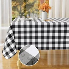 a black and white checkered table cloth on a dining room table next to a vase with an orange flower