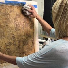 a woman is working on a piece of wood with a rag in her left hand