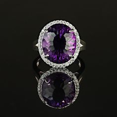 This is part of Chairish’s Fine Jewelry assortment.  Elegant Evening Cocktail Ring of oval Amethyst, 12.40ct, surrounded by sparkling genuine zircons, 0.57ct.  This unique amethyst is a special cut with extra sparkle and flashes of pink in the purple.  The setting is sterling silver featuring a lovely lattice design. Amethyst is the February birthstone and is said to protect from intoxication and evil spells. It will calm your spirit and give you focus. Pure quartz is colorless, but the most pri Luxury Purple Gemstones With Halo Setting, Luxury Purple Amethyst Ring With Halo Setting, Oval Gemstones With Diamond Accents Luxury Style, Luxury Oval Gemstones With Halo Setting, Oval Purple Diamond Ring With Gemstone Accents, Oval Diamond Gemstones With Accents, Purple Oval Diamond Ring, Oval Amethyst Ring With Gemstone Accents For Formal Occasions, Dazzling Oval Gemstones With Halo Setting