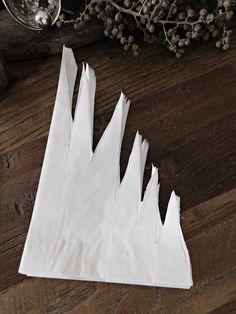 white paper is folded in the shape of mountains on a wooden table next to some branches