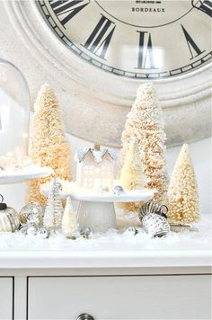 a white clock sitting on top of a wall next to christmas trees and other decorations