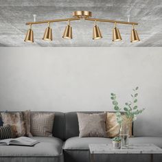 a living room with a couch, coffee table and lamps on the ceiling above it