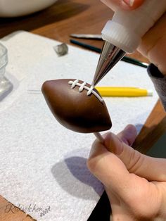 someone is decorating a football shaped chocolate cake with icing on the top and bottom