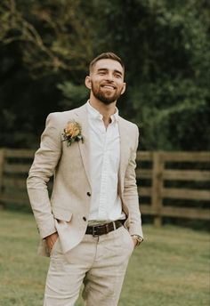 a man in a tan suit and flower boutonniere smiles at the camera