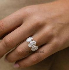 a close up of a person's hand wearing a ring with three stones on it