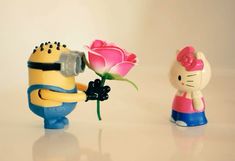 two minion figurines one holding a flower and the other with a camera