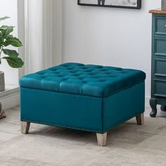 a blue ottoman sitting on top of a wooden floor next to a potted plant